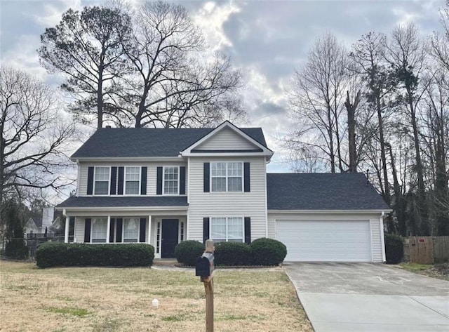 colonial home featuring a garage, driveway, a front yard, and fence