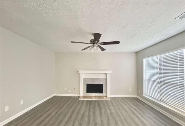 unfurnished living room with a ceiling fan, a fireplace with flush hearth, wood finished floors, and baseboards