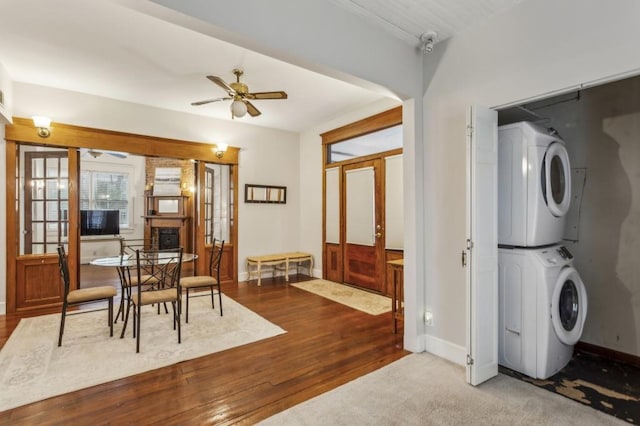 interior space with wood-type flooring, stacked washer and clothes dryer, and ceiling fan