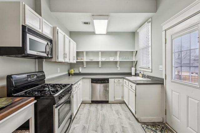 kitchen featuring stainless steel appliances, sink, white cabinets, and light hardwood / wood-style floors