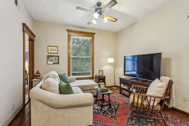 living room with ceiling fan, dark hardwood / wood-style flooring, and a textured ceiling