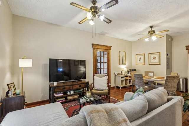 living room featuring ceiling fan, dark hardwood / wood-style floors, and a textured ceiling