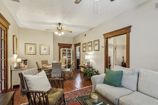 living room featuring ceiling fan, dark hardwood / wood-style flooring, and a textured ceiling