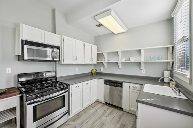 kitchen featuring dark countertops, open shelves, white cabinetry, and stainless steel appliances