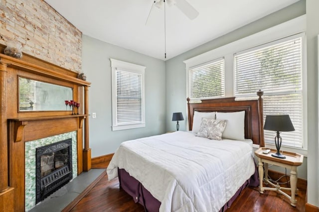 bedroom featuring ceiling fan, a fireplace, dark wood finished floors, and baseboards