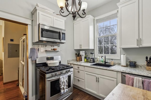 kitchen with hanging light fixtures, stainless steel appliances, white cabinets, and electric panel