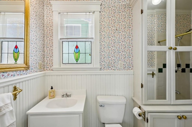 bathroom featuring toilet, wallpapered walls, vanity, and wainscoting