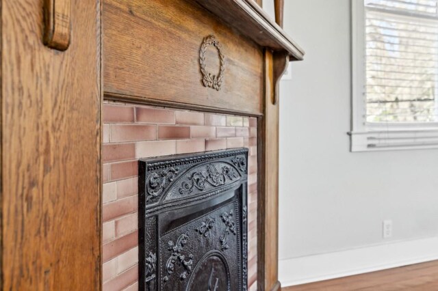 bedroom with a brick fireplace, dark hardwood / wood-style floors, and ceiling fan