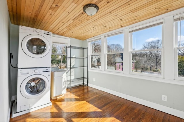 laundry room featuring laundry area, baseboards, wood ceiling, stacked washer / drying machine, and wood finished floors