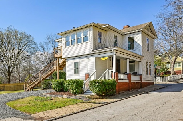 view of front facade featuring a chimney, fence, stairway, and a porch