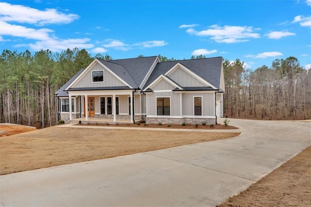view of front facade with a porch, driveway, and board and batten siding