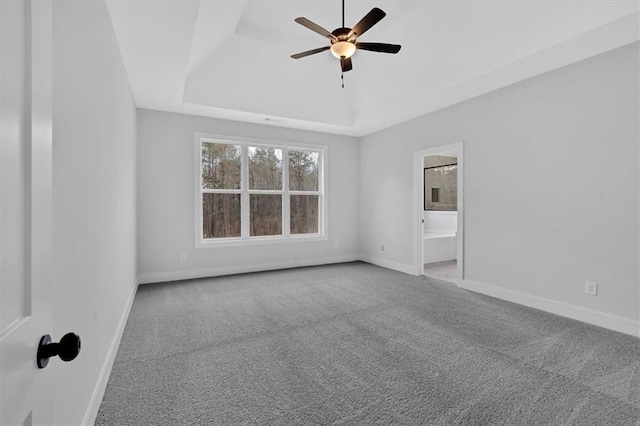 empty room featuring carpet flooring, a ceiling fan, baseboards, and a raised ceiling