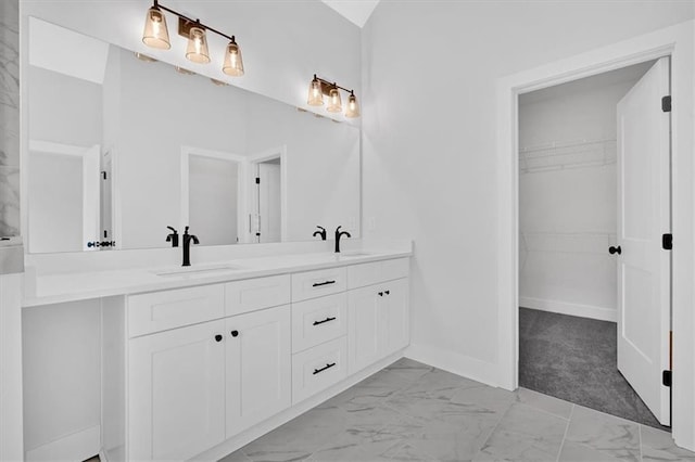full bath featuring double vanity, marble finish floor, a spacious closet, and a sink