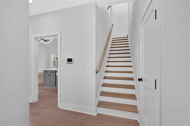 stairway with wood finished floors, baseboards, and recessed lighting
