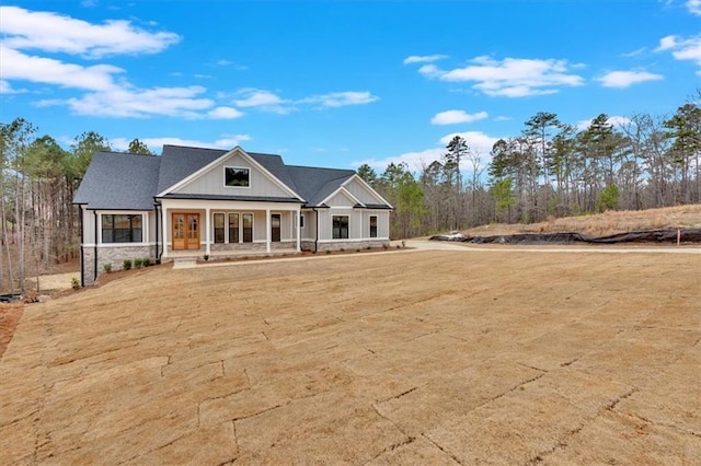 view of front of home featuring covered porch and stone siding