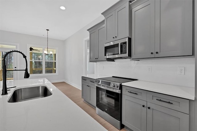 kitchen featuring a sink, light wood finished floors, stainless steel appliances, and gray cabinetry