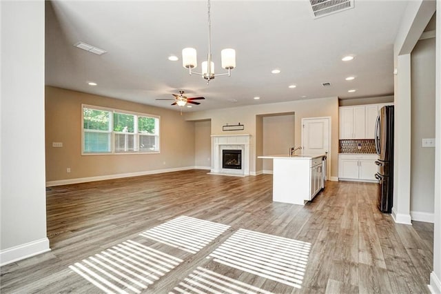 1858 Belmore St SE, Smyrna, GA 30080 - unfurnished living room featuring ceiling fan, a high end fireplace, light wood-style floors, a chandelier, and recessed lighting