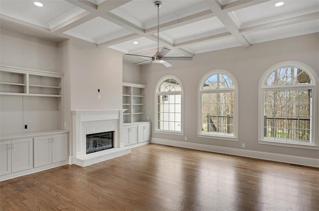 unfurnished living room with plenty of natural light, a fireplace, wood finished floors, and baseboards