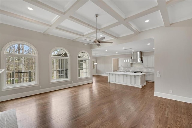 unfurnished living room featuring beam ceiling, ceiling fan, wood finished floors, coffered ceiling, and baseboards