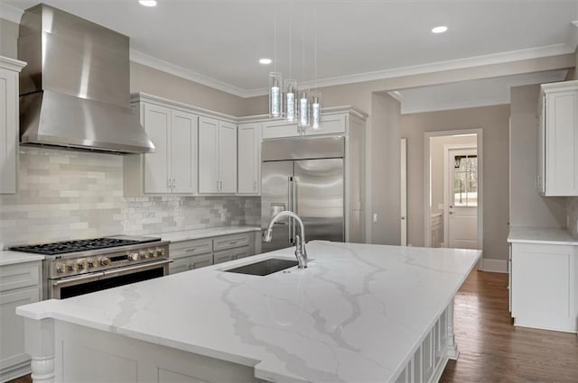 kitchen featuring ornamental molding, wall chimney range hood, a sink, and high quality appliances