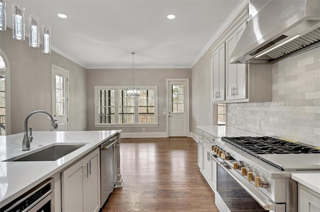 kitchen featuring stainless steel appliances, a sink, wall chimney exhaust hood, and ornamental molding