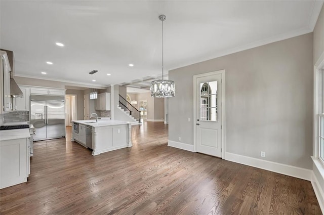 kitchen with dark wood-style floors, ornamental molding, stainless steel appliances, light countertops, and backsplash