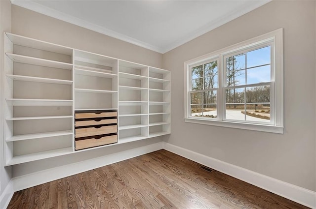 unfurnished room featuring baseboards, crown molding, visible vents, and wood finished floors