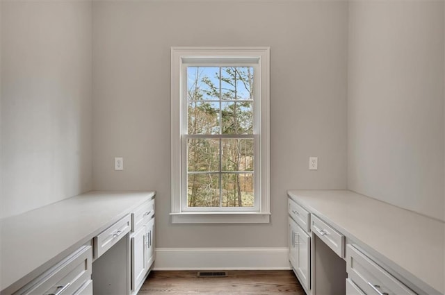 interior space with a healthy amount of sunlight, visible vents, baseboards, and wood finished floors