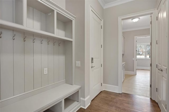 mudroom with dark wood-style flooring, crown molding, and baseboards