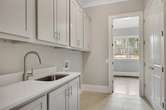 laundry area with hookup for a washing machine, a sink, baseboards, ornamental molding, and cabinet space