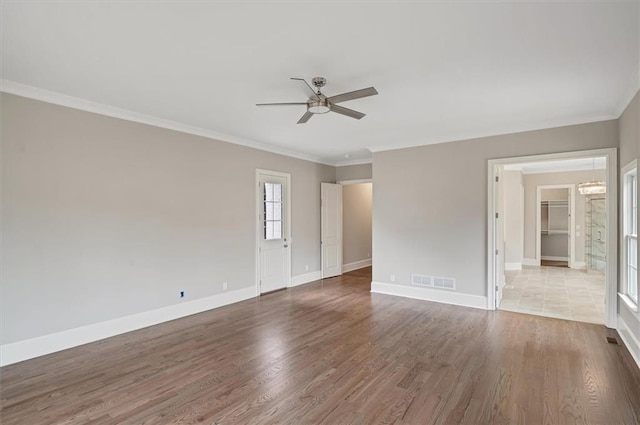 unfurnished room featuring ceiling fan with notable chandelier, wood finished floors, visible vents, and baseboards