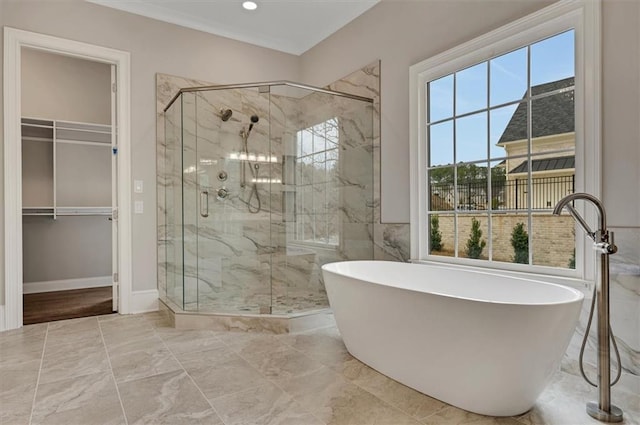 full bathroom with a walk in closet, a stall shower, marble finish floor, and a freestanding tub