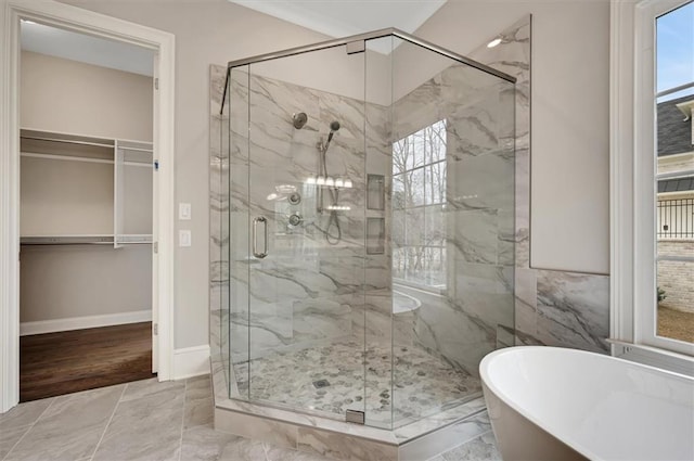 full bath featuring a soaking tub, a marble finish shower, a walk in closet, and baseboards