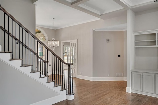 foyer entrance with wood finished floors, visible vents, baseboards, an inviting chandelier, and crown molding