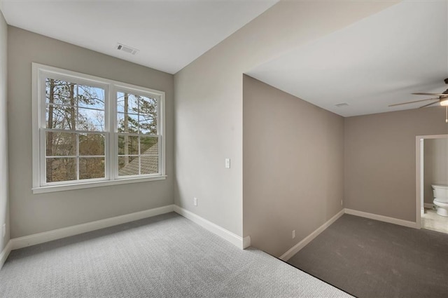 carpeted spare room with baseboards, visible vents, and a ceiling fan