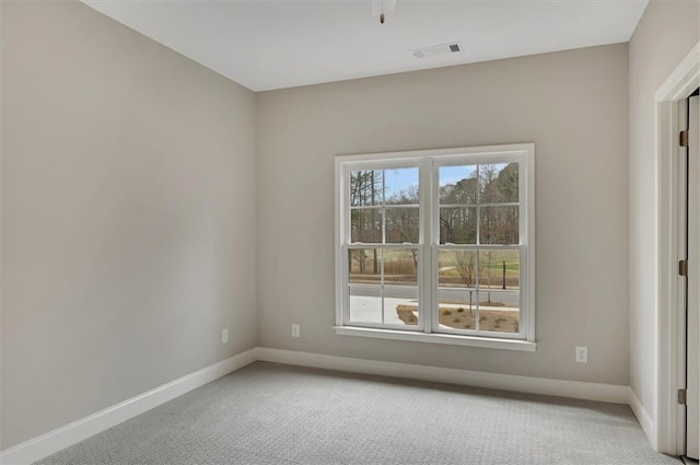 unfurnished room featuring a wealth of natural light, light carpet, visible vents, and baseboards