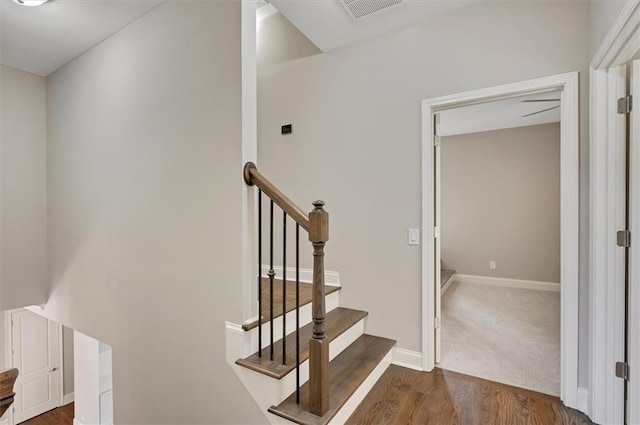 stairs with wood finished floors, visible vents, and baseboards