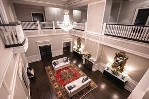 living room with an inviting chandelier, a decorative wall, and wood finished floors