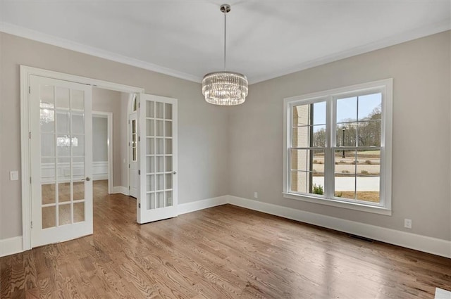 empty room with a notable chandelier, wood finished floors, visible vents, baseboards, and french doors