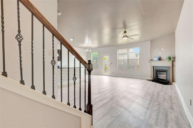 529 Dasheill Ln, Atlanta, GA 30349 - unfurnished living room with wood finished floors, stairs, a fireplace with flush hearth, and a ceiling fan