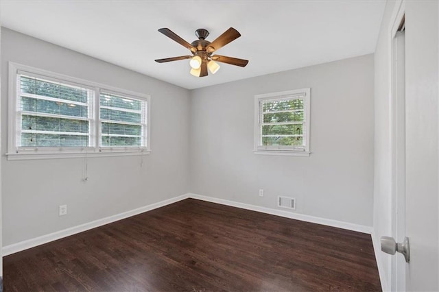 empty room featuring a wealth of natural light, dark hardwood / wood-style floors, and ceiling fan