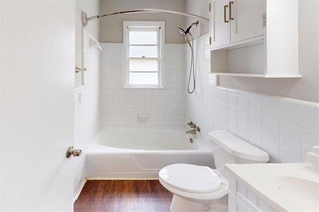 full bathroom featuring tiled shower / bath, wood-type flooring, tile walls, toilet, and vanity