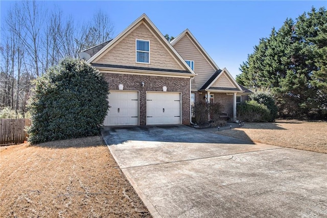 view of front of home featuring a garage, driveway, brick siding, and fence