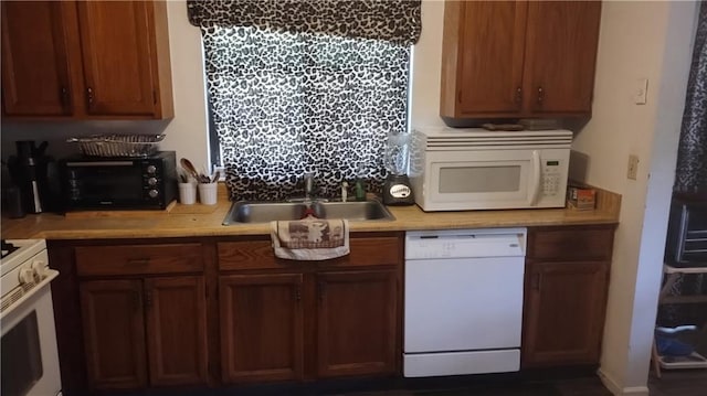 kitchen featuring a sink, white appliances, and light countertops