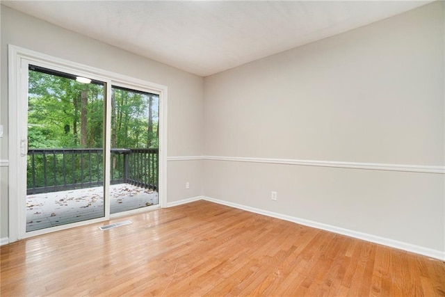 spare room with light wood-style flooring, visible vents, and baseboards