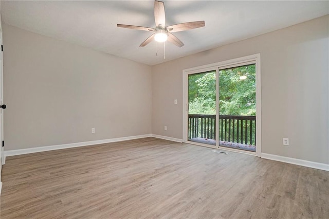 empty room with ceiling fan, wood finished floors, visible vents, and baseboards