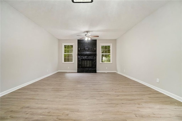 unfurnished living room featuring a ceiling fan, a fireplace, baseboards, and wood finished floors