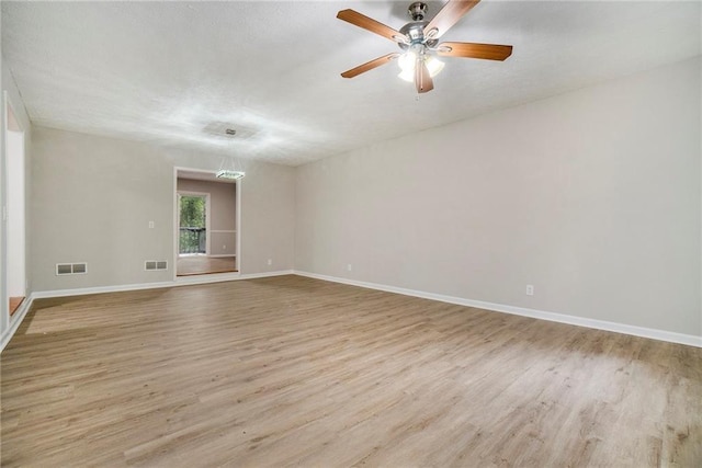 unfurnished room featuring baseboards, visible vents, and wood finished floors