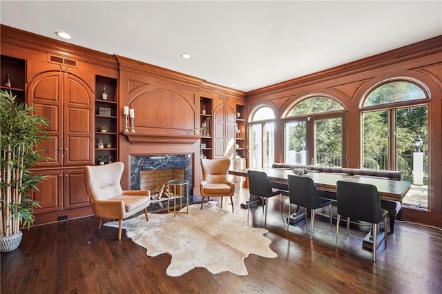 living area featuring dark hardwood / wood-style flooring, crown molding, plenty of natural light, and a premium fireplace