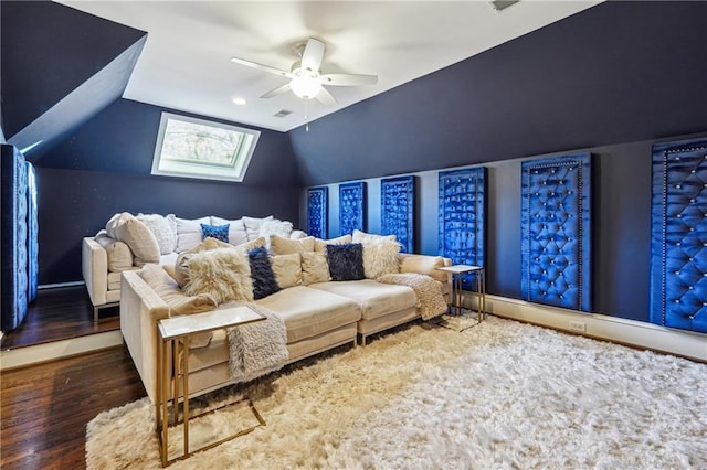 cinema room featuring ceiling fan, dark hardwood / wood-style floors, and lofted ceiling with skylight